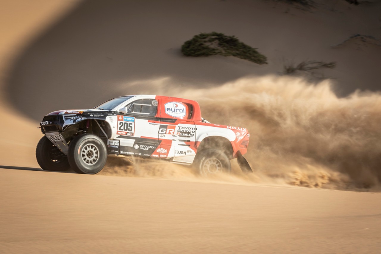 Hilux profile shot driving through desert kicking up sand